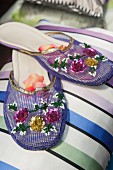 Indian-style purple slippers embroidered with sequinned flowers on striped cushion