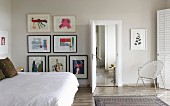 Doppelbett mit weisser Tagesdecke, seitlich an Wand Bildersammlung, in modernem Schlafzimmer
