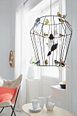Pendelleuchte mit Drahtgestell als Vogelkäfig, dekoriert mit bunten Glasvögeln