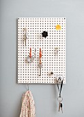 DIY key rack made from white perforated panel and various hooks and knobs