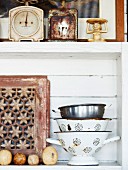 Vintage metal colanders and old kitchen scales on wooden kitchen shelves