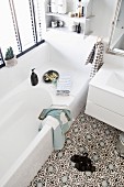 White bathroom with Moroccan-style ornamental floor tiles and wall-mounted shelves above bathtub