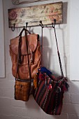 Various bags hanging on vintage wooden coat rack with pattern of roses
