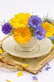 Sträussschen aus blauen Kornblumen & gelben Ringelblumen in nostalgischer Tasse