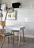 Avantgardistische Stühle am Tisch und Regalablage montiert an Holzleiste, gerahmtes Bild und Wandboards im Hintergrund