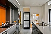 Modern kitchen in pale grey with orange accents