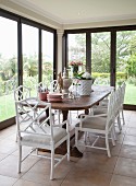 Dining table and white cane chairs in conservatory with tiled floor