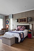 Vintage-style teenager's bedroom with Union-Flag scatter cushions on bed and old wooden trunk at foot