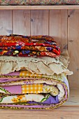 Colourful folded quilts in a wooden cupboard