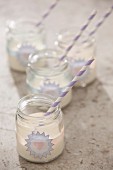 Vanilla milkshakes in jam jars decorated with stickers and striped drinking straws