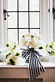 Bridal bouquet of white roses with black and white ribbon on windowsill
