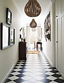 Gallery of pictures and low-hanging ceiling lamps in hallway with chequered floor