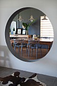 View of dining table and chairs seen through round aperture in wall