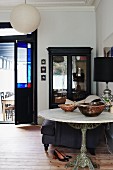 Bowls on marble bistro table with cast iron pedestal base in front of black display case