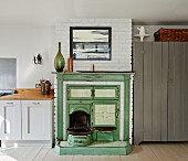 Vintage range in masonry fireplace painted green next to kitchen counter in rustic interior
