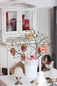 Branches in vase with garland of stamped wooden discs as festive table decoration