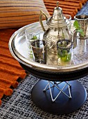Moroccan teapot and tea glasses on silver tray on modern side table