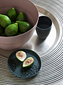 Beaker, green figs in bowl and cut fig on plate on silver tray