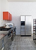 Stainless steel counter, red wall-mounted cabinets and fridge-freezer in kitchen area