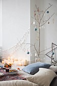 Festive picnic in living room with bare branch used as Christmas tree and many candles