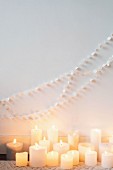 Garland of white paper discs on wall above lit candles