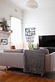 Sofa mit schwarz-weiss gemusterter Fransendecke und politischem Plakat neben Fernseher