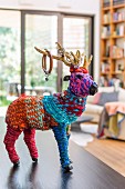 Artistic animal figurine covered in colourful wool on surface