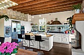 Bar stools at island counter in open-plan kitchen with wood-beamed ceiling