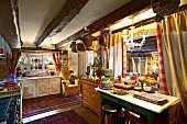 Cluttered country-house kitchen with low, wood-beamed ceiling