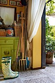 Gardening equipment leaned against green-painted cabinet in storage room