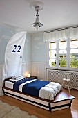Custom boat-shaped child's bed with blue and white bed linen in maritime child's bedroom