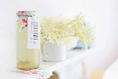 Elderflowers and home-made elderflower syrup in romantically decorated bottle