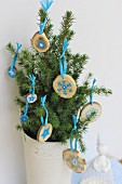 Small fir tree in white, vintage pot decorated with small wooden discs painted with pale blue motifs