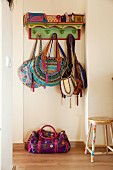 Various ethnic handbags hanging on brightly painted wooden coat rack