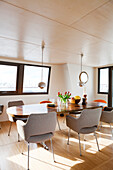 Chairs with pale grey upholstery around wooden table in retro dining area of houseboat