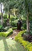 Exotische Gartenanlage mit Brunnen in Form einer Amphore unter Palmen