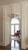 View of dusky pink, wing-back armchair through grand arched doorway