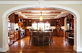Blick in edle, geräumige Landhausküche mit Holzfronten und Hängeschränken, glänzender Edelholzparkett