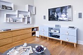Flatscreen TV above media cabinet, sideboard and shelving modules on wall