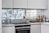 Spiegelfliesen als Spritzschutz zwischen Oberschränken und Kochfeld in Einbauküche
