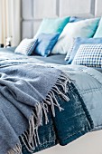 Double bed with blankets and scatter cushions in shades of blue