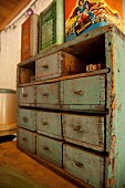 Vintage tins on top of small, rustic chest of drawers with peeling paint
