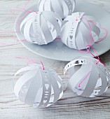 Hand-made, paper baubles with cut-out patterns and bright pink cords