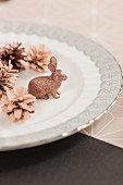 Arrangement of copper-coloured pine cones and rabbit figurine on plate