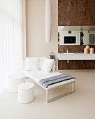 White chaise and side table in luxurious bathroom with rust-effect tiles