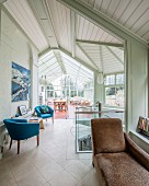 Brown chaise, blue fifties' armchairs in room leading into conservatory