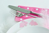 Pink bunny motifs and delicate feathers stuck to edge of plate with removable spray adhesive as Easter decorations