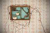 Old wooden drawer hung on wall and decorated with autumnal twigs, roots and squashes