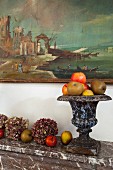 Hydrangea flowers, apples and antique urn decorating marble mantelpiece below painting on wall