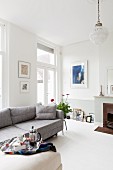 Grey sofa and fireplace in bright, modern living room in period building